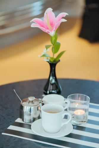 a table with a vase with a pink flower and a cup of coffee at Hotel Pod Sosnami in Osieck