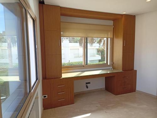 uma cozinha com uma janela e armários de madeira em La Fondation em El Harhoura