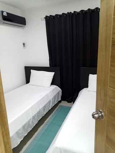 2 camas en una habitación con cortinas negras en Cómodo y acogedor apartamento, en Mendoza
