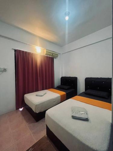 een hotelkamer met 2 bedden en een rood gordijn bij Teresek View Motel in Kuala Tahan