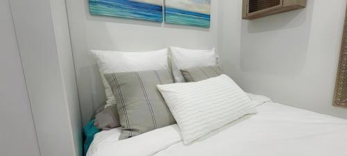 uma cama branca com almofadas e um quadro na parede em Loft independiente FORGET ME NOT em Getxo