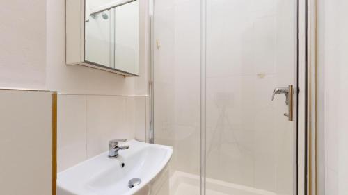 a white bathroom with a sink and a shower at Small & Cosy 1 Bedroom Flat in London