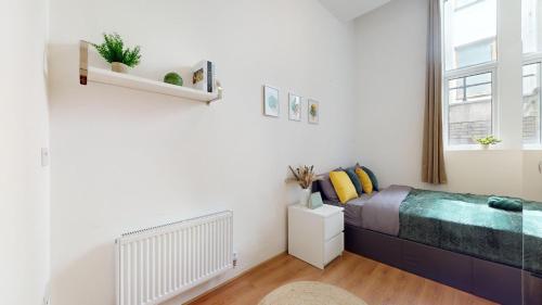 um quarto branco com uma cama e uma janela em Small & Cosy 1 Bedroom Flat em Londres