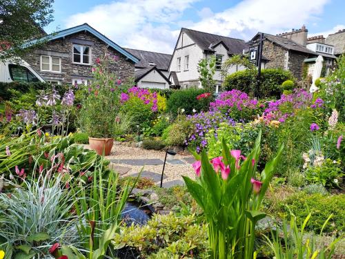 a garden with flowers in front of a house at Puddle Duck Lodge – Adults Only in Bowness-on-Windermere