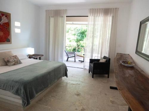 a bedroom with a bed and a chair and a window at Hukumeizi Minca in Santa Marta