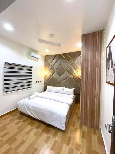 um quarto com uma grande cama branca e pisos em madeira em CEO HOMES AND APARTMENT em Warri