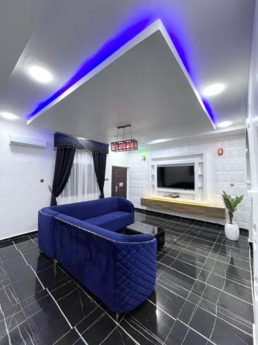 sala de estar con sofá azul y TV en CEO HOMES AND APARTMENT, en Warri