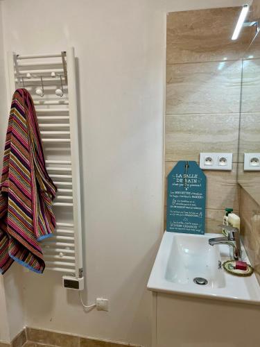 a bathroom with a sink and a sign on the wall at Gîte Ensemont in Saramon
