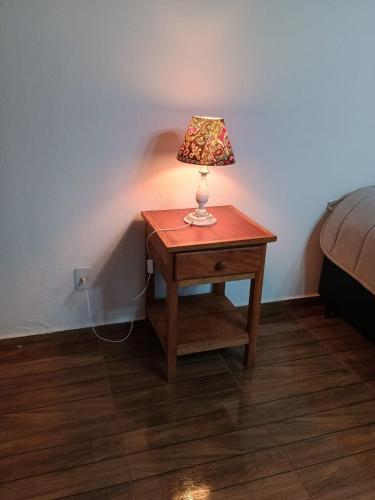 uma lâmpada sobre uma mesa ao lado de uma cama em Chalé Torneados em Tiradentes
