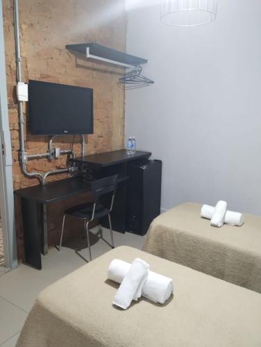 a room with two beds and a desk with a computer at Hotel Monte Castelo in Rio de Janeiro