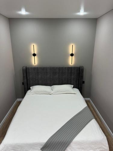 Bett in einem Zimmer mit zwei Lichtern an der Wand in der Unterkunft Комфорт in Oral