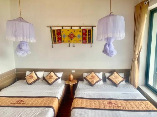 two beds in a room with curtains and a window at Puluong Aroma in Hương Bá Thước