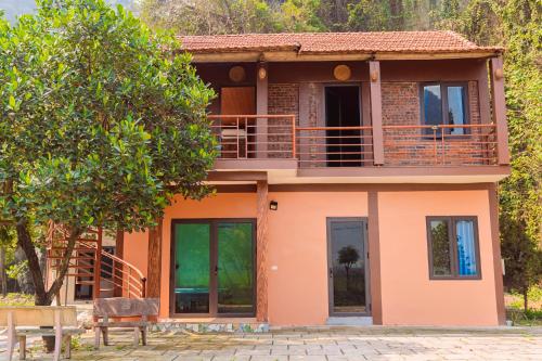 a orange house with a balcony and a tree at Tam Coc Moutainside Homestay in Ninh Binh