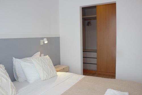 a bedroom with a bed with white pillows and a closet at Relax & Travel in Almada