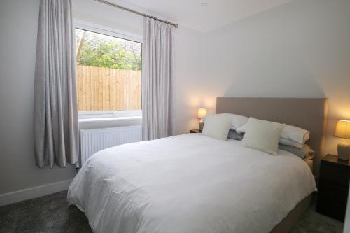 1 dormitorio con cama blanca y ventana en The Secret Cottage 5A, en Seaford
