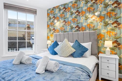 a bedroom with a bed with blue pillows and a floral wallpaper at 1 Bedroom Apartment Near Heathrow London - TW18 in Staines