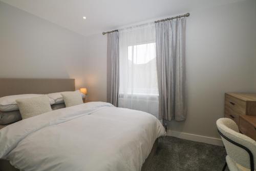 1 dormitorio con cama blanca y ventana en The Secret Cottage 4A, en Seaford