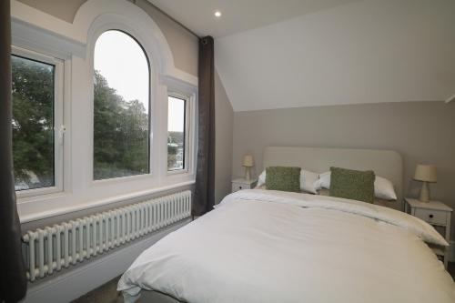 a bedroom with a large bed and two windows at 8 The Cuckmere in Seaford