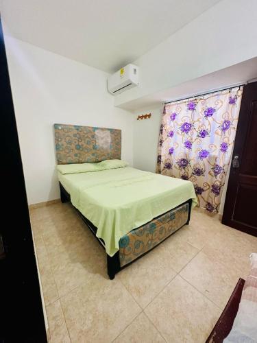 a bedroom with a bed with a green bedspread at HOSTAL CASA ALFON BURITACA in Santa Marta
