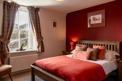 a bedroom with a bed with red walls and a window at Bridgend House B&B in Drumnadrochit
