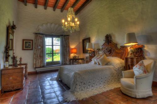een slaapkamer met een bed, een stoel en een kroonluchter bij Hacienda Acamilpa in Acamilpa
