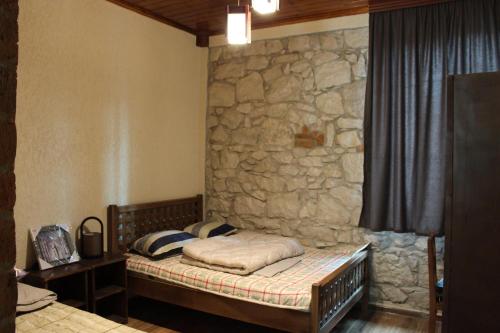 Cama en habitación con pared de piedra en Royal Edena, en Ambrolauri