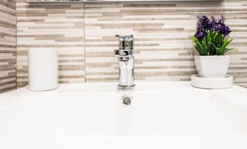 a bathroom sink with a faucet and two flowers at Welcomely - Badde Nuraghe dimora vista mare con parcheggio privato in Magomadas