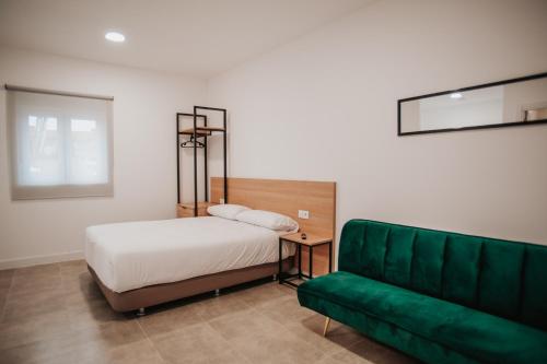 a bedroom with a bed and a green couch at Polorooms in Zaratán