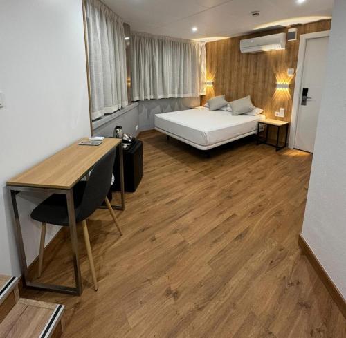 Schlafzimmer mit einem Bett, einem Schreibtisch und einem Tisch in der Unterkunft Hotel Medicis in Barcelona