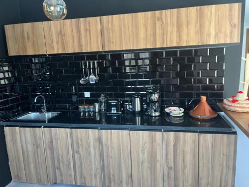 a kitchen counter with a sink and a black brick wall at Villa B à 5km du centre in Marrakech