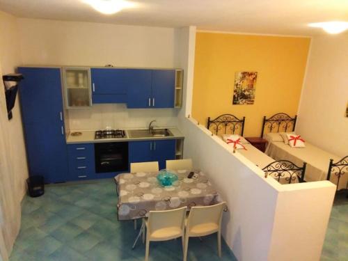 una cucina con armadi blu, tavolo e sedie di Sweet Star House a Castellammare del Golfo