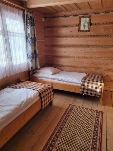 a room with two beds in a log cabin at Dom Wypoczynkowy "U Gruszki" in Dzianisz