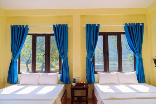 two beds in a room with blue curtains at Tam Coc Moutainside Homestay in Ninh Binh
