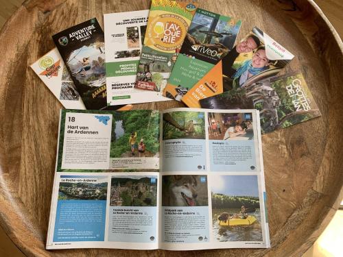 a bunch of brochures on top of a wooden bowl at Heerlijk vakantiehuis in bos bij Durbuy in Durbuy