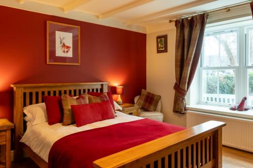 a bedroom with a bed with red walls and a window at Bridgend House B&B in Drumnadrochit