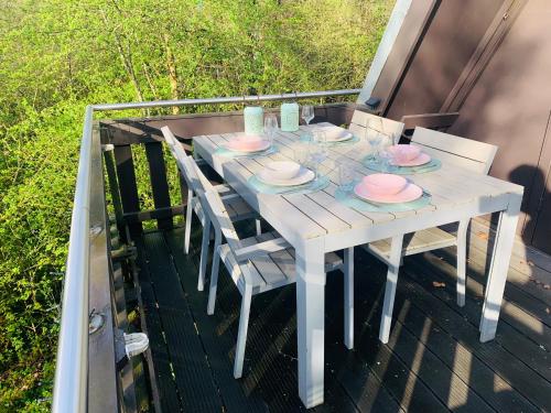 a white table with chairs and plates on a deck at Heerlijk vakantiehuis in bos bij Durbuy in Durbuy