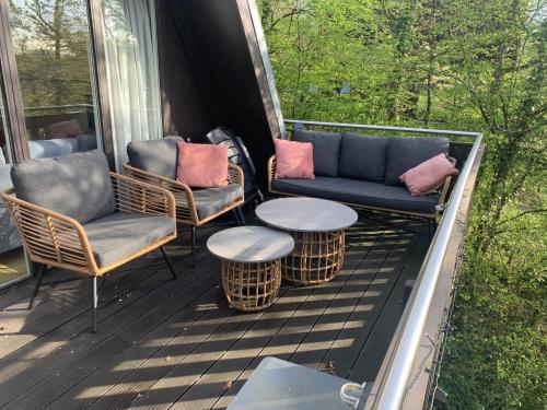a porch with chairs and a couch and a table at Heerlijk vakantiehuis in bos bij Durbuy in Durbuy