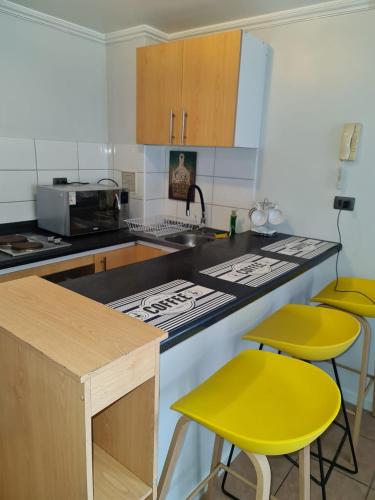 uma cozinha com dois bancos amarelos e um balcão em Costa azul 1 em Iquique