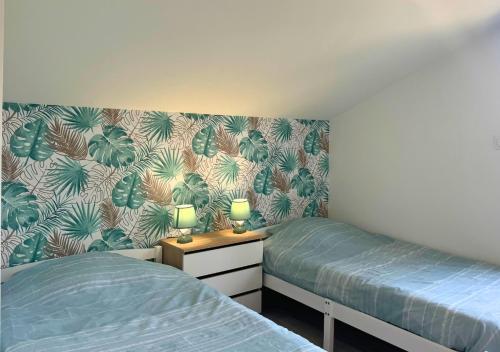 - une chambre avec 2 lits jumeaux et du papier peint tropical dans l'établissement Chalet Paisible proche du Lac, à Biscarrosse