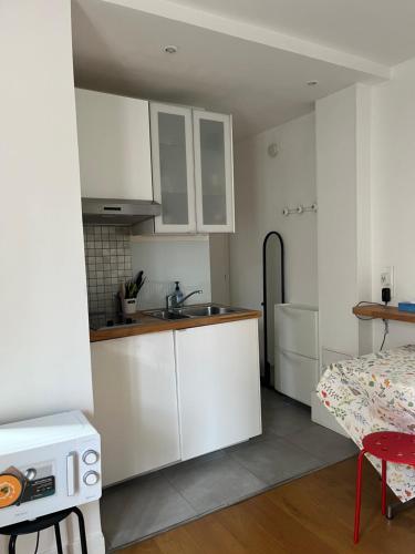 une cuisine avec des armoires blanches et un évier dans l'établissement Studio indépendant cœur Paris 13ème, à Paris