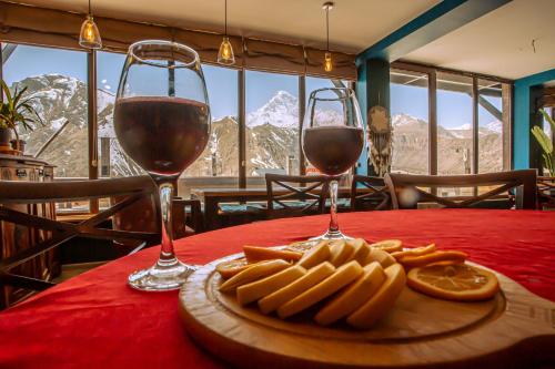 two glasses of wine and food on a table at Chemodann Kazbegi in Stepantsminda