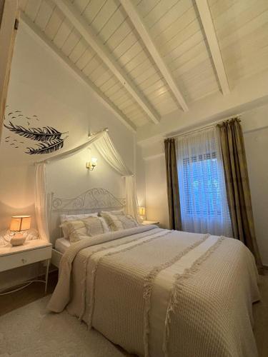 a white bedroom with a bed and a window at Alacati Zeynep in Alaçatı