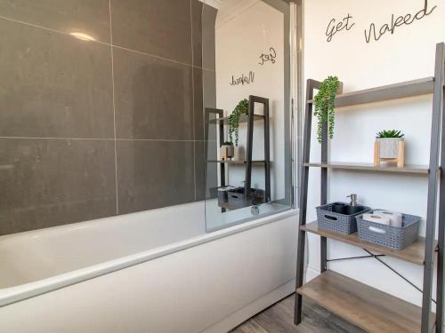 a bathroom with a tub and shelves with plants at Pass the Keys Fabulous location stylish home in Spennymoor