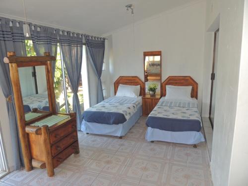 a bedroom with two beds and a mirror at Woodgrange Garden Cottages in Hibberdene