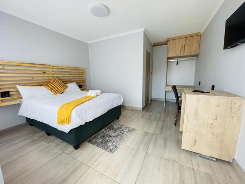 Schlafzimmer mit einem Bett, einem Schreibtisch und einem TV in der Unterkunft Shafas Guest House in Rundu