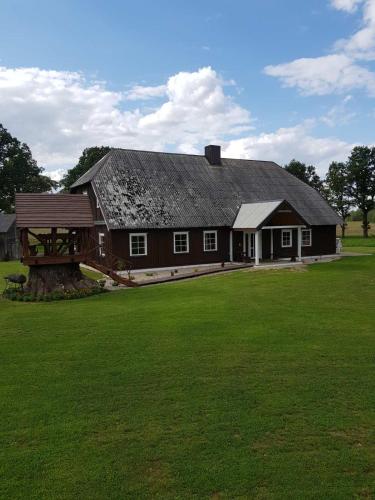 een groot huis met een groot groen veld ervoor bij Jonaičių dvaras in Telšiai