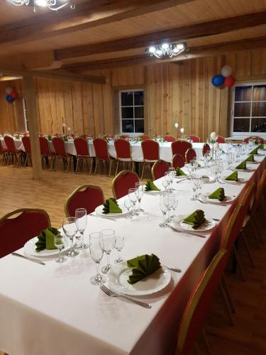 een lange tafel in een kamer met rode stoelen bij Jonaičių dvaras in Telšiai