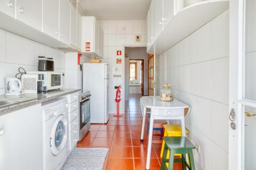 ポルトにあるCamarao Apartmentのキッチン(白い家電製品、テーブル、椅子付)