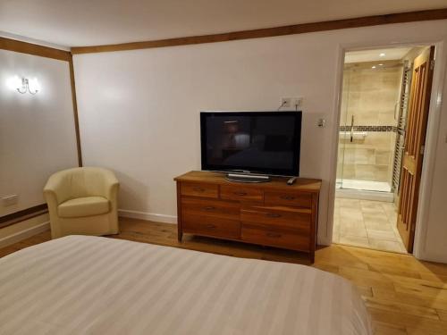 a bedroom with a bed and a flat screen tv at The Barn New Forest Free Paddle boarding & free Zip wire. in Ringwood
