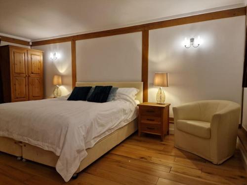 a bedroom with a large bed and a chair at The Barn New Forest Free Paddle boarding & free Zip wire. in Ringwood